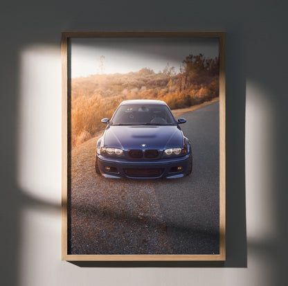 BMW E46 M3 art print poster featuring a blue car on a winding road, framed wall art with warm lighting.