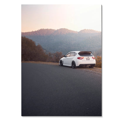 White Subaru WRX STI parked on roadside with mountain landscape at sunset poster wall art.