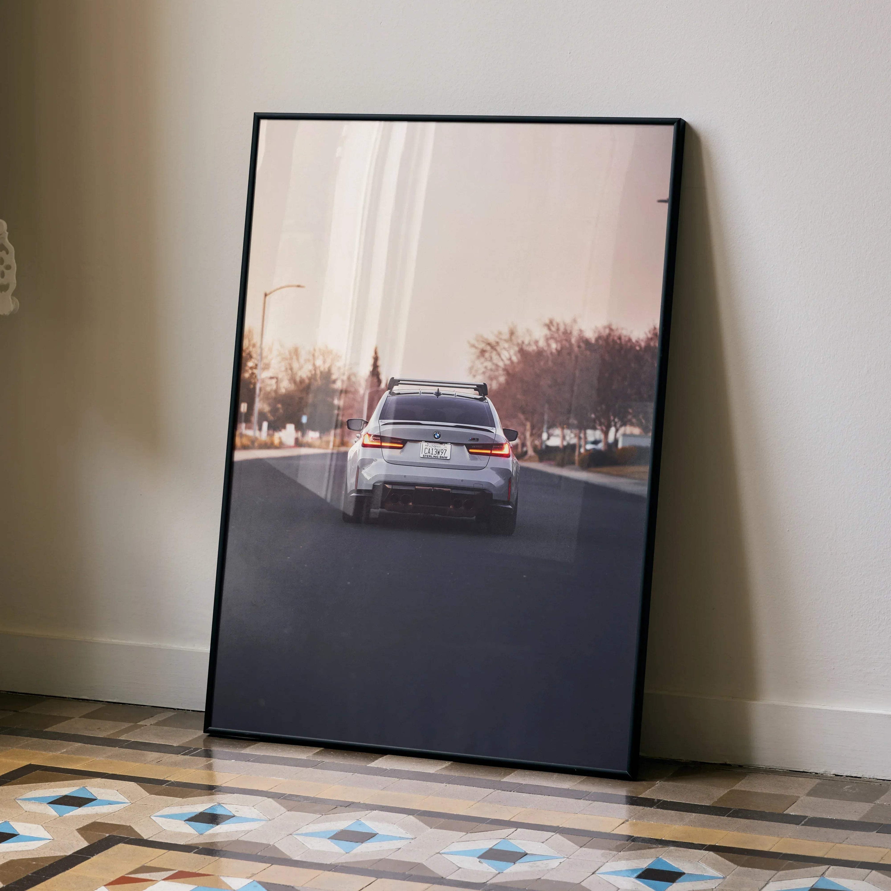 BMW G80 M3 driving on sunlit road poster with modern cityscape wall art.