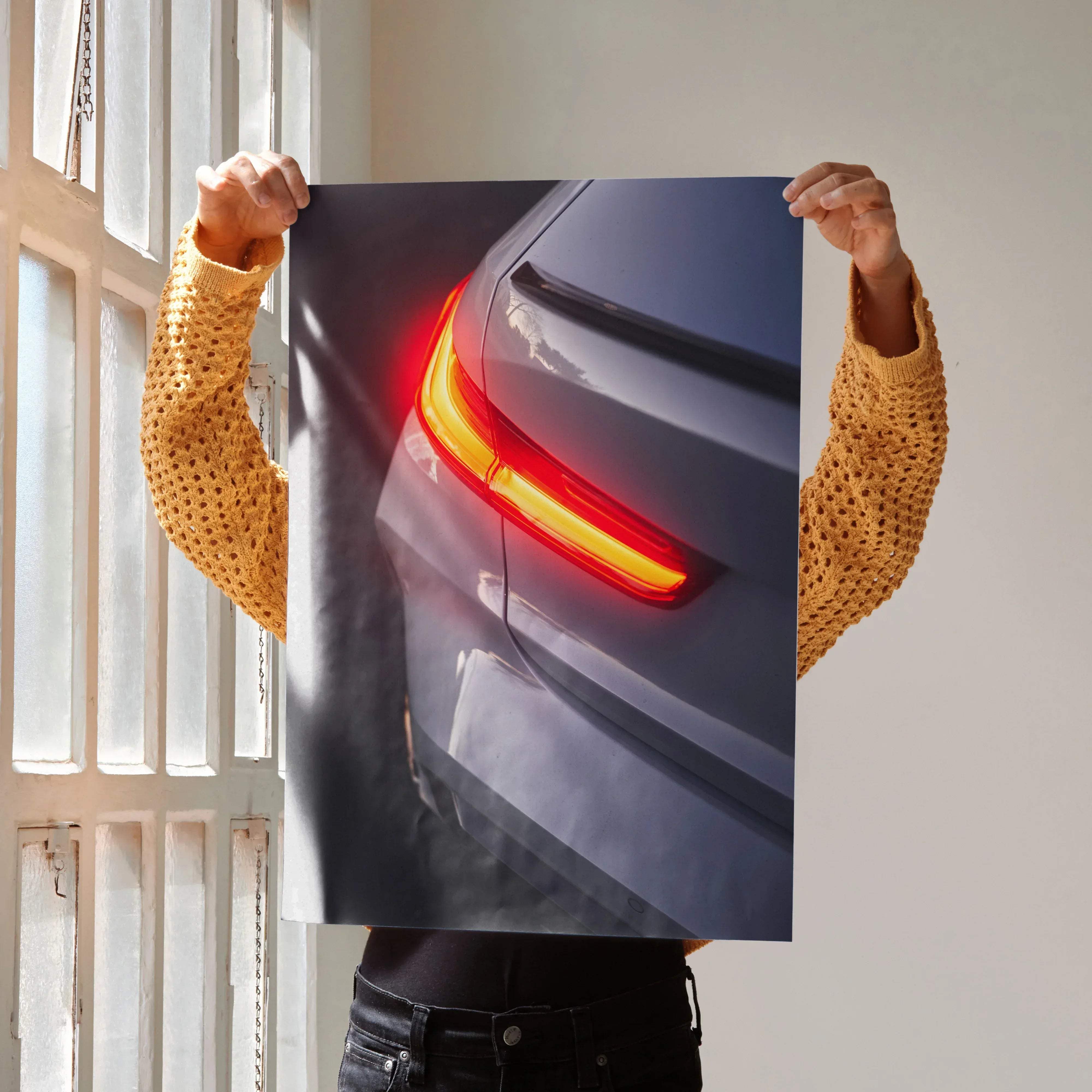 A sleek dark gray audi car poster showing the back with illuminated red and yellow taillights for automotive design fans