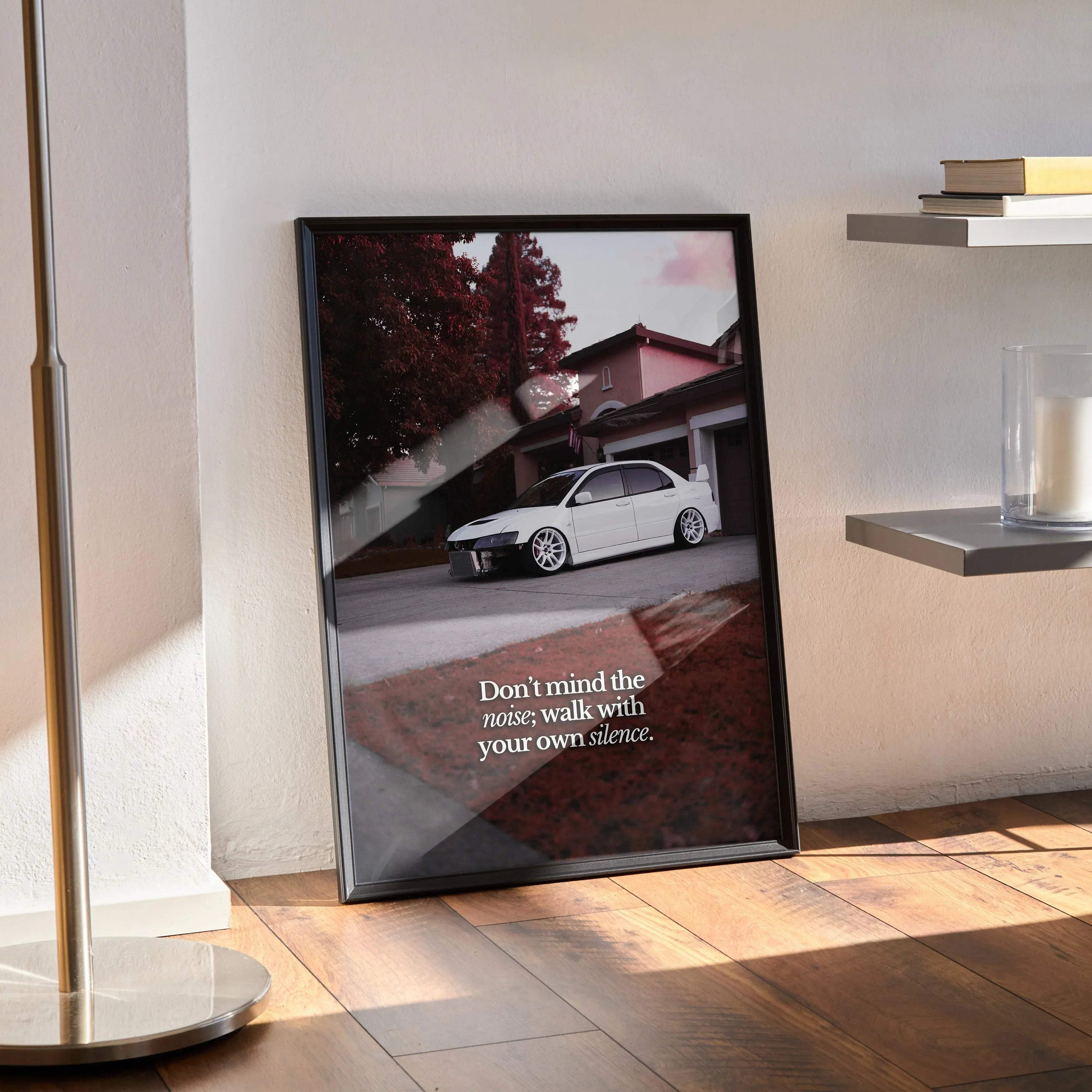 Motivational poster featuring white Mitsubishi Evo 8 with inspiring text in black frame leaned against wall wall art.