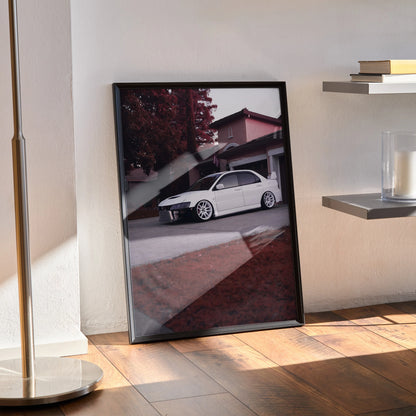 Mitsubishi Evo 8 poster wall art with white car in urban setting, black frame, leaning on floor.