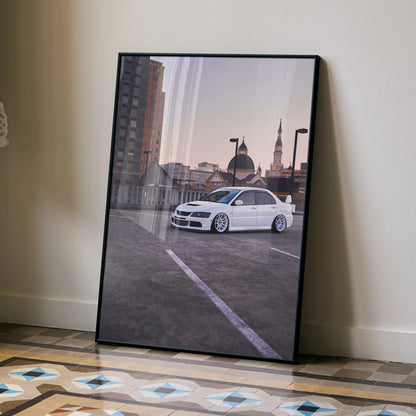 Framed wall art poster of a white Mitsubishi Evo 8 parked on rooftop at sunset with city skyline background.