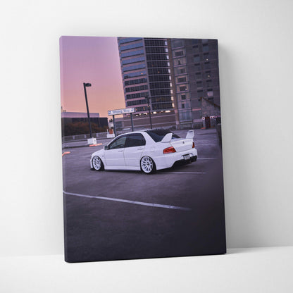 Vertical canvas wall art featuring a white Mitsubishi Evo 8 parked near urban buildings at dusk.