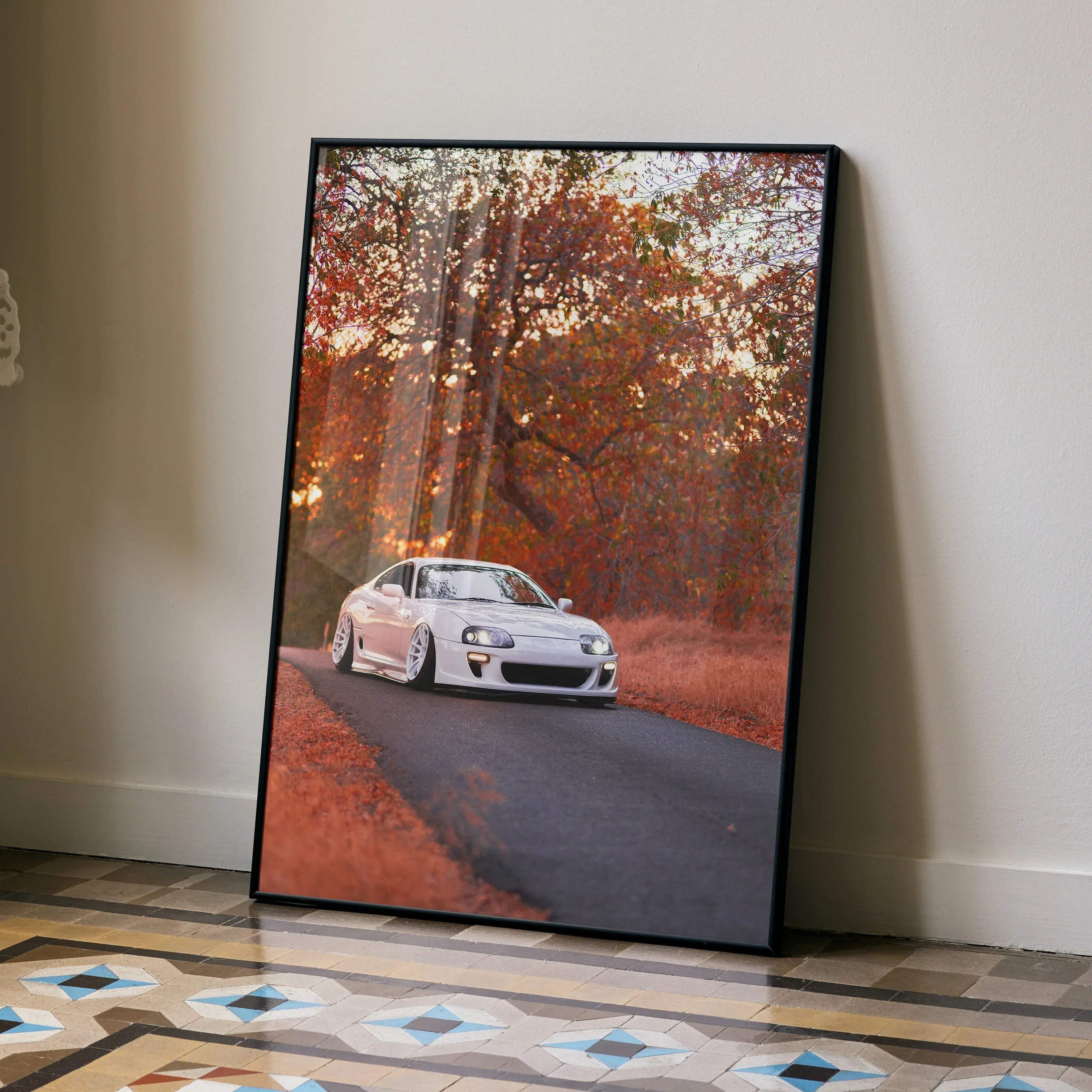 Toyota Supra MK4 poster wall art with white sports car on autumn road in black frame.