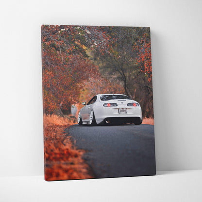 Toyota Supra MK4 driving on road surrounded by autumn trees canvas wall art.