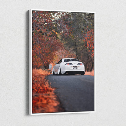 Vertical canvas wall art featuring a white Toyota Supra MK4 on a road surrounded by autumn trees and foliage.