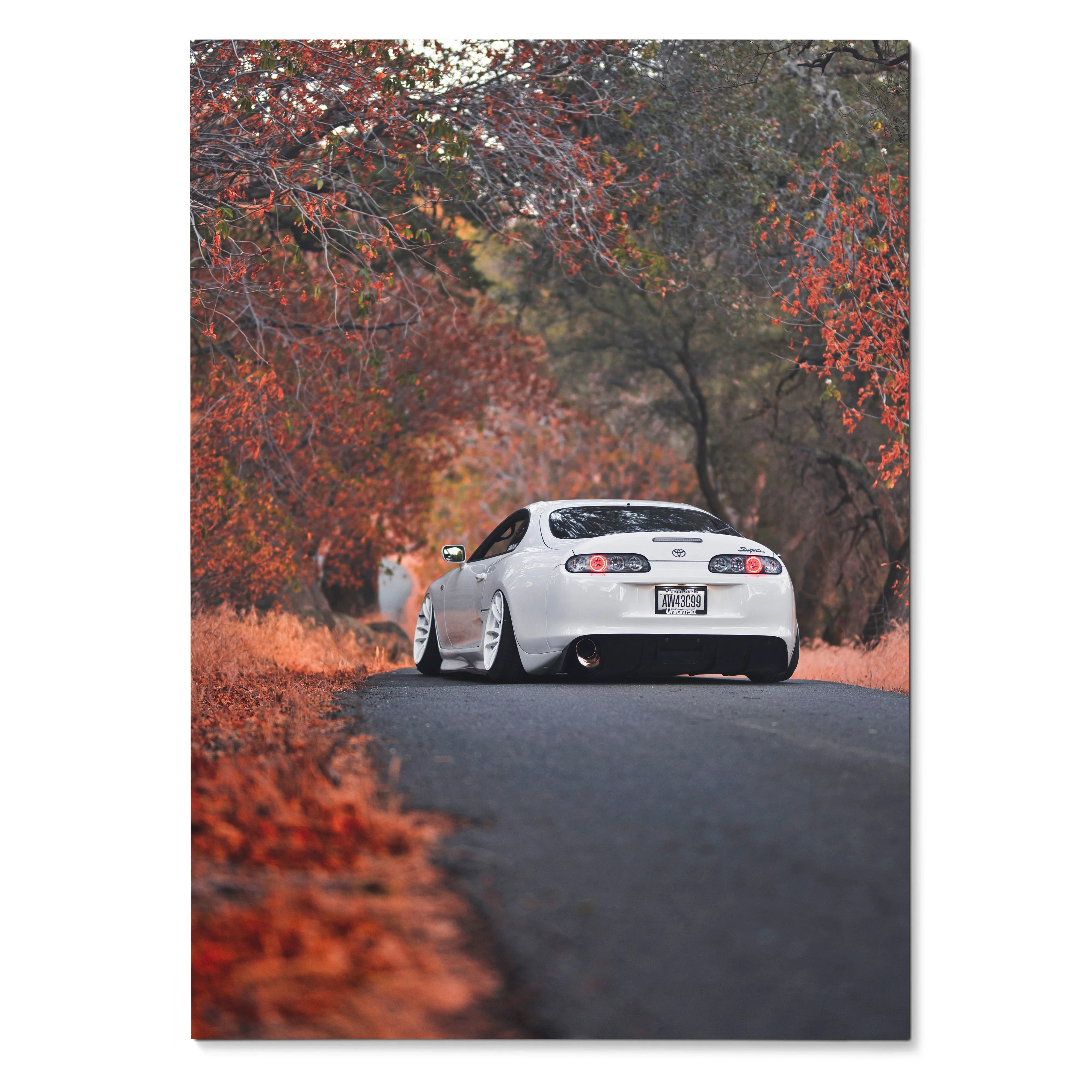 White Toyota Supra MK4 driving on autumn road surrounded by red and orange trees poster wall art.