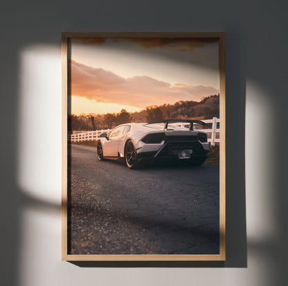 Lamborghini Huracan poster wall art featuring rear view of white sports car at sunset with scenic background.