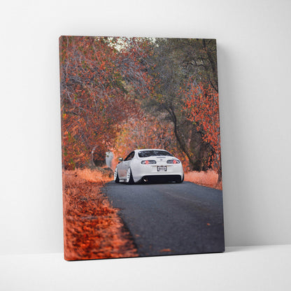 Vertical canvas art featuring a white Toyota Supra MK4 driving on a road surrounded by autumn trees, wall art for car.