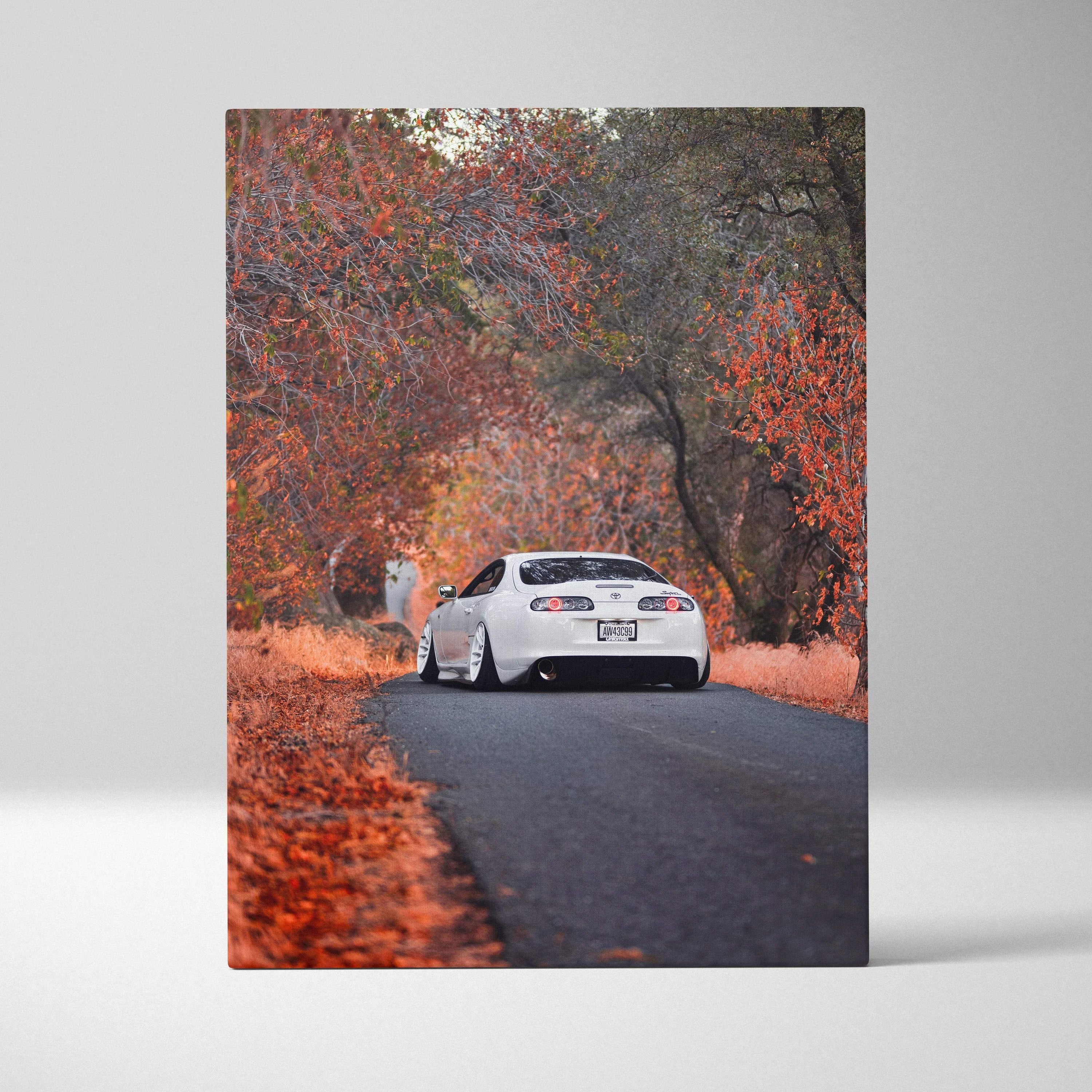 Toyota Supra MK4 driving on autumn road canvas wall art with vibrant fall foliage.