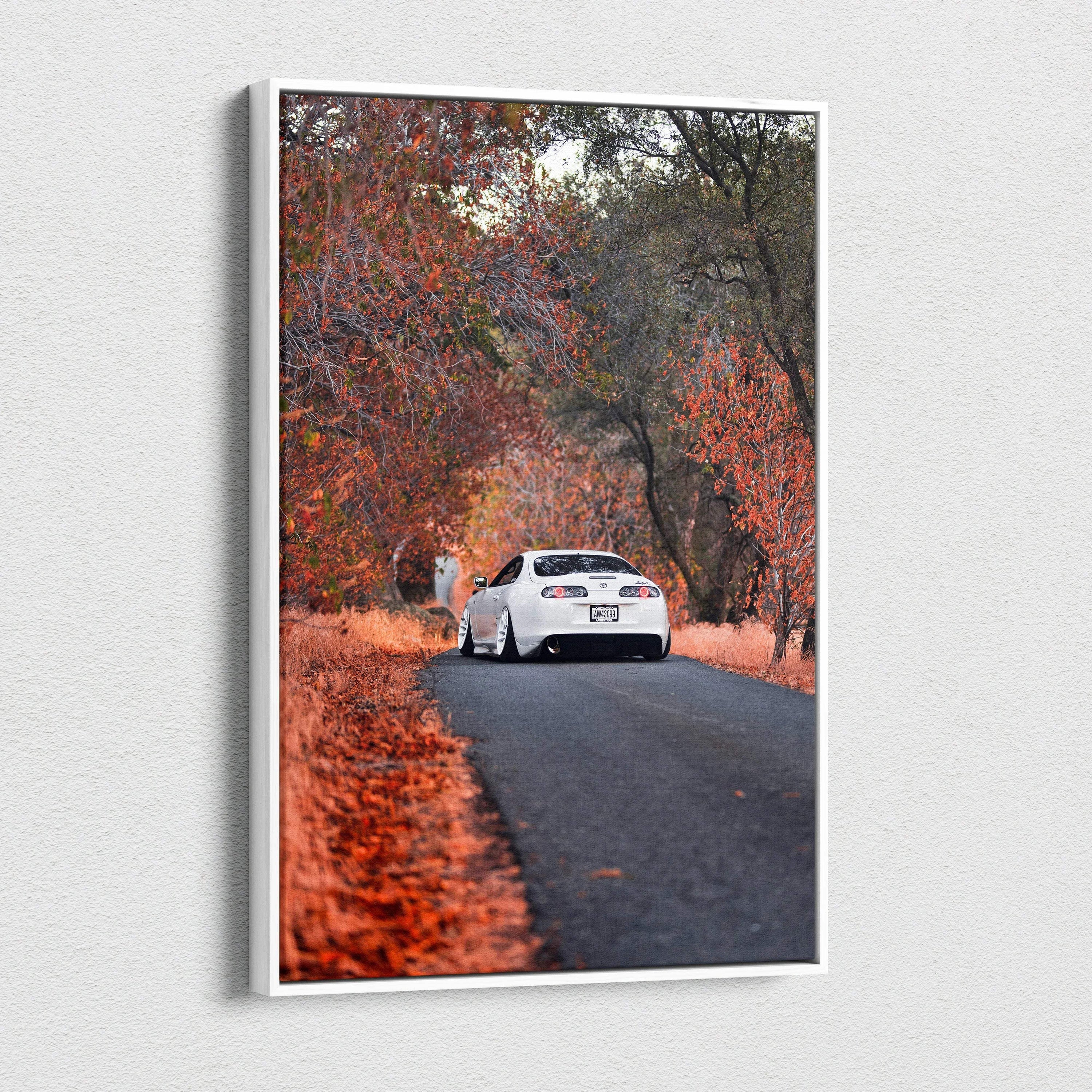 Vertical canvas wall art featuring a white Toyota Supra MK4 on a forest road with vibrant autumn foliage.
