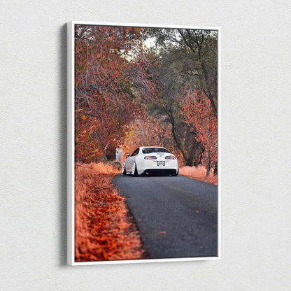 Vertical canvas wall art featuring a white Toyota Supra MK4 on a forest road with vibrant autumn foliage.