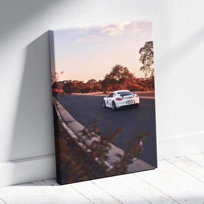 Porsche GT4 sports car at sunset on road canvas wall art with warm orange sky.