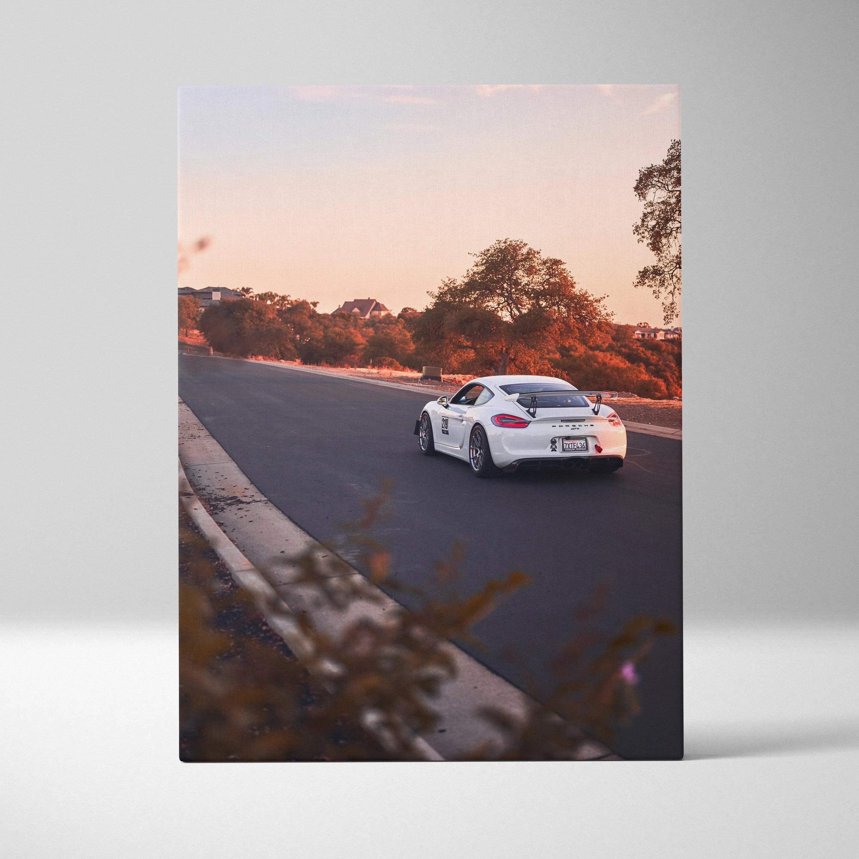 White Porsche GT4 driving on sunset-lit road, vertical canvas wall art print.