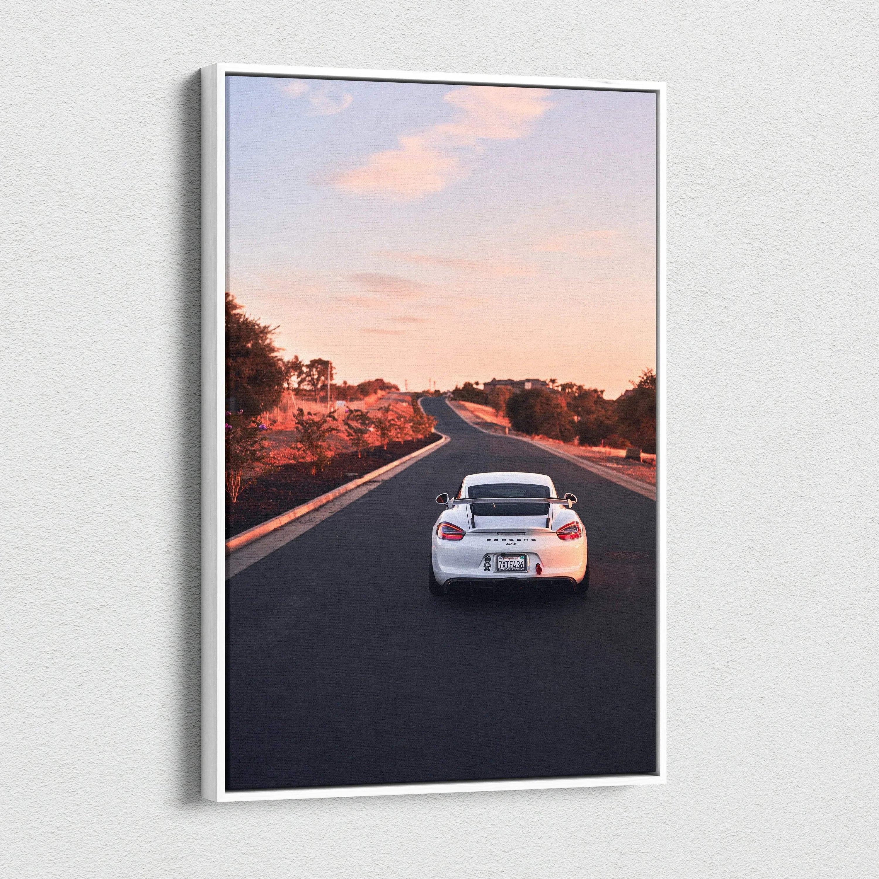 Vertical canvas wall art featuring a white Porsche GT4 driving on an open road at sunset.