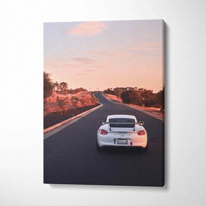 Vertical canvas wall art featuring white Porsche GT4 driving on an empty road at sunset.
