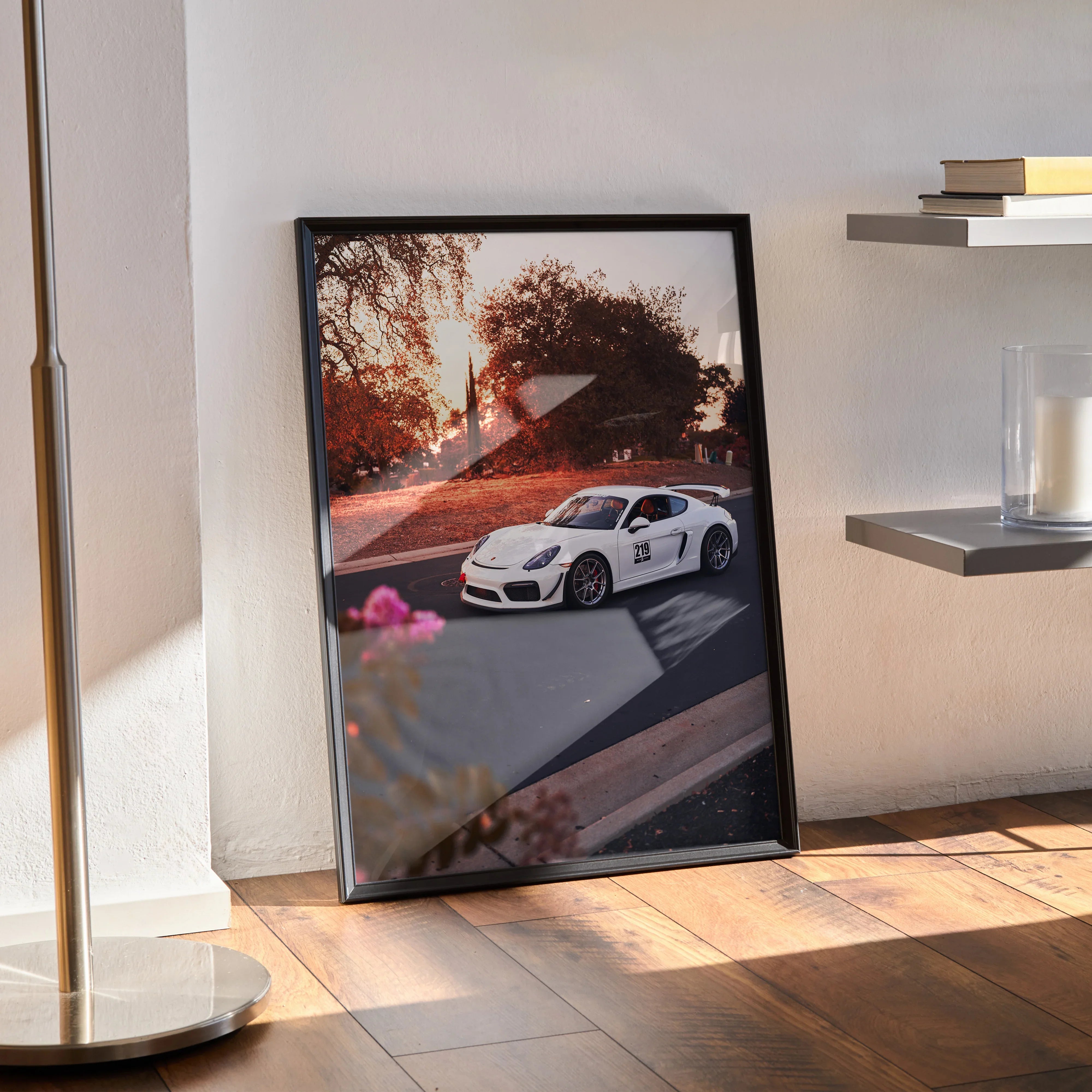 Porsche Cayman GT4 poster with sunset backdrop in sleek black frame leaning on floor wall art.