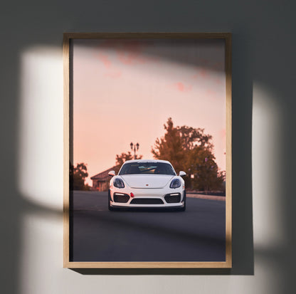 Porsche Cayman GT4 driving on road at sunset wall art poster in wooden frame.