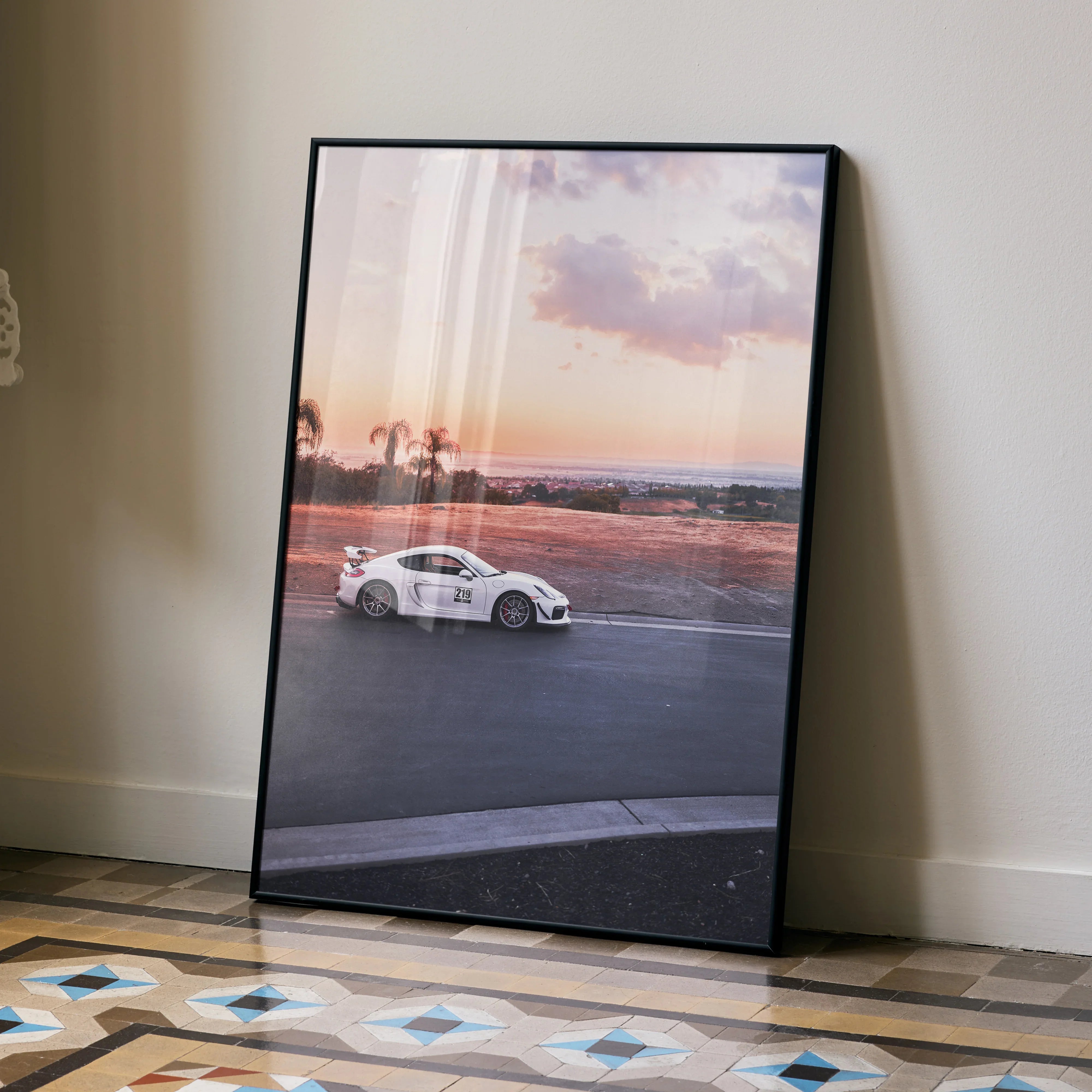 Porsche GT4 racing car on track at sunset poster wall art in black frame.