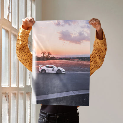 Porsche GT4 racing car on track at sunset poster wall art with dramatic sky colors.