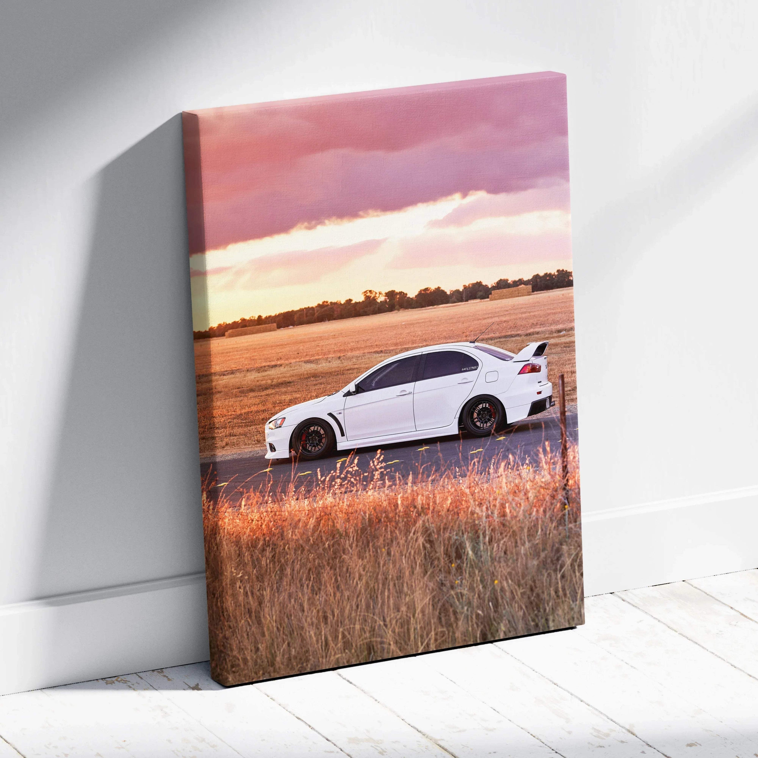 Vertical canvas wall art featuring a white Mitsubishi Evo 10 sports car on a rural road at sunset.