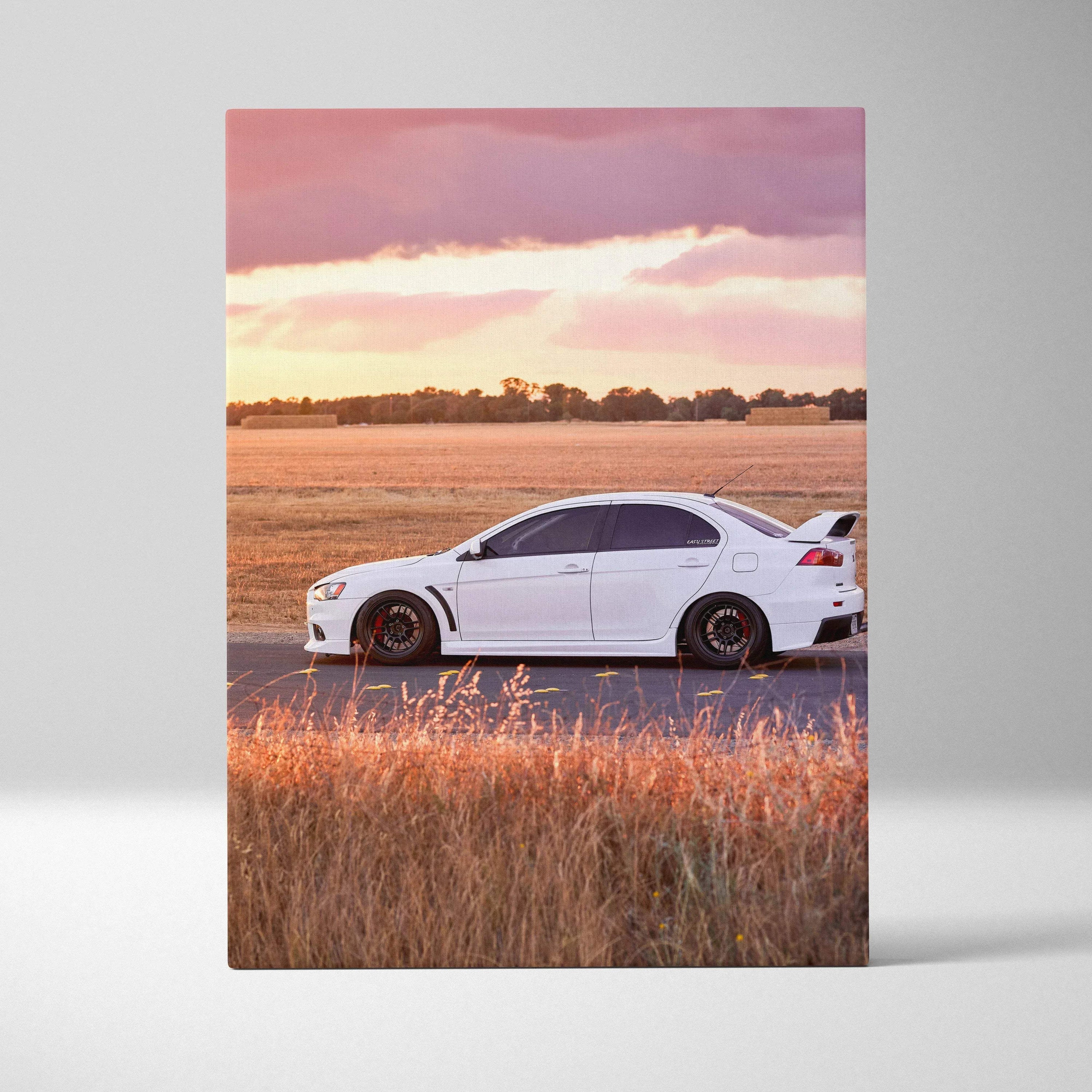 Vertical canvas art of white Mitsubishi Evo 10 on road with sunset sky and field background.