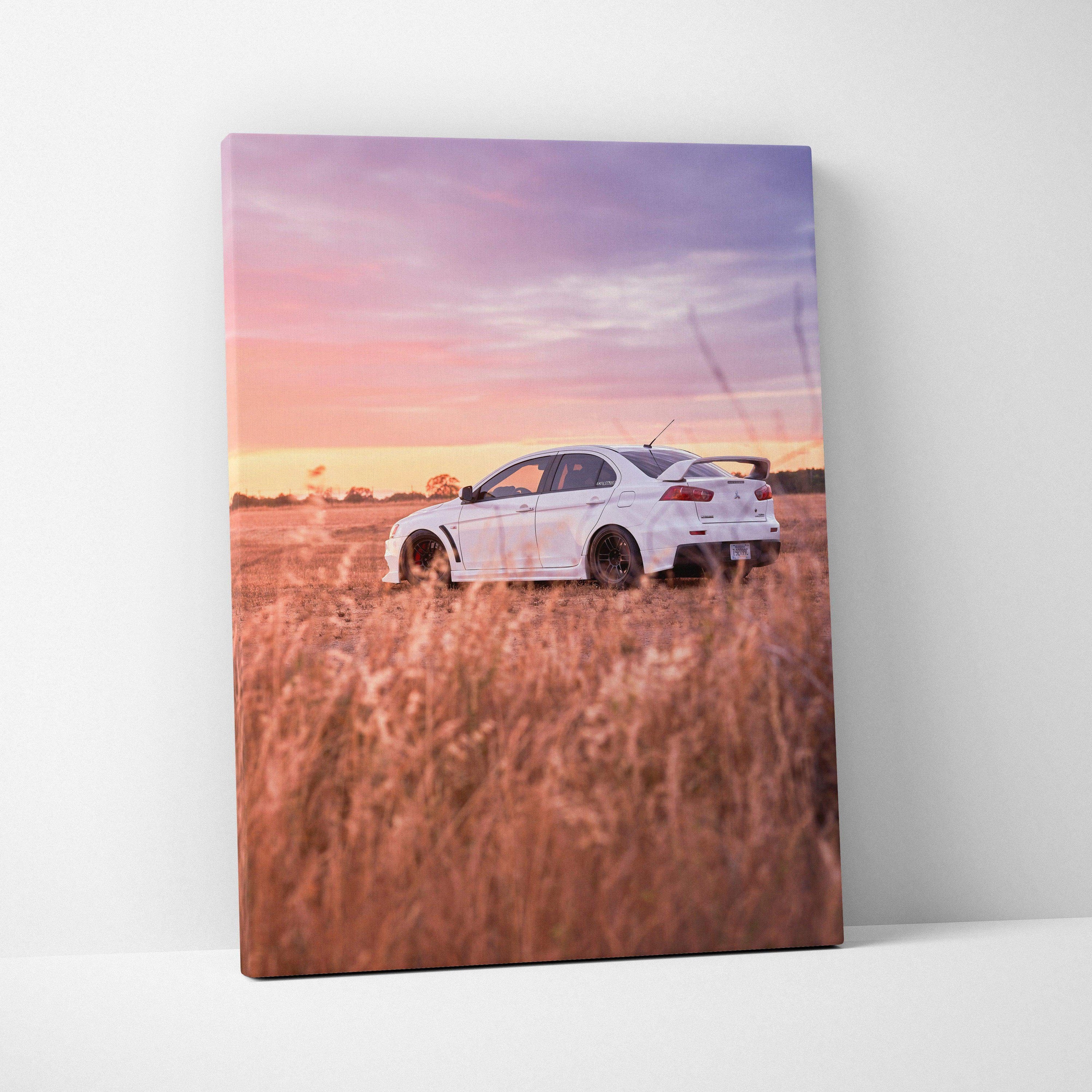 White Mitsubishi Evo 10 parked in tall grass at sunset on vertical canvas wall art.