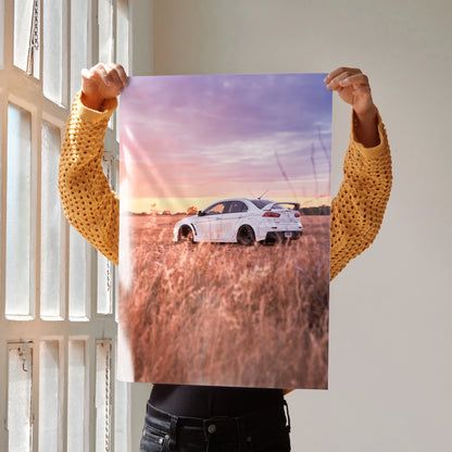 Mitsubishi Evo 10 in tall grass at sunset poster wall art with vibrant purple and orange sky.