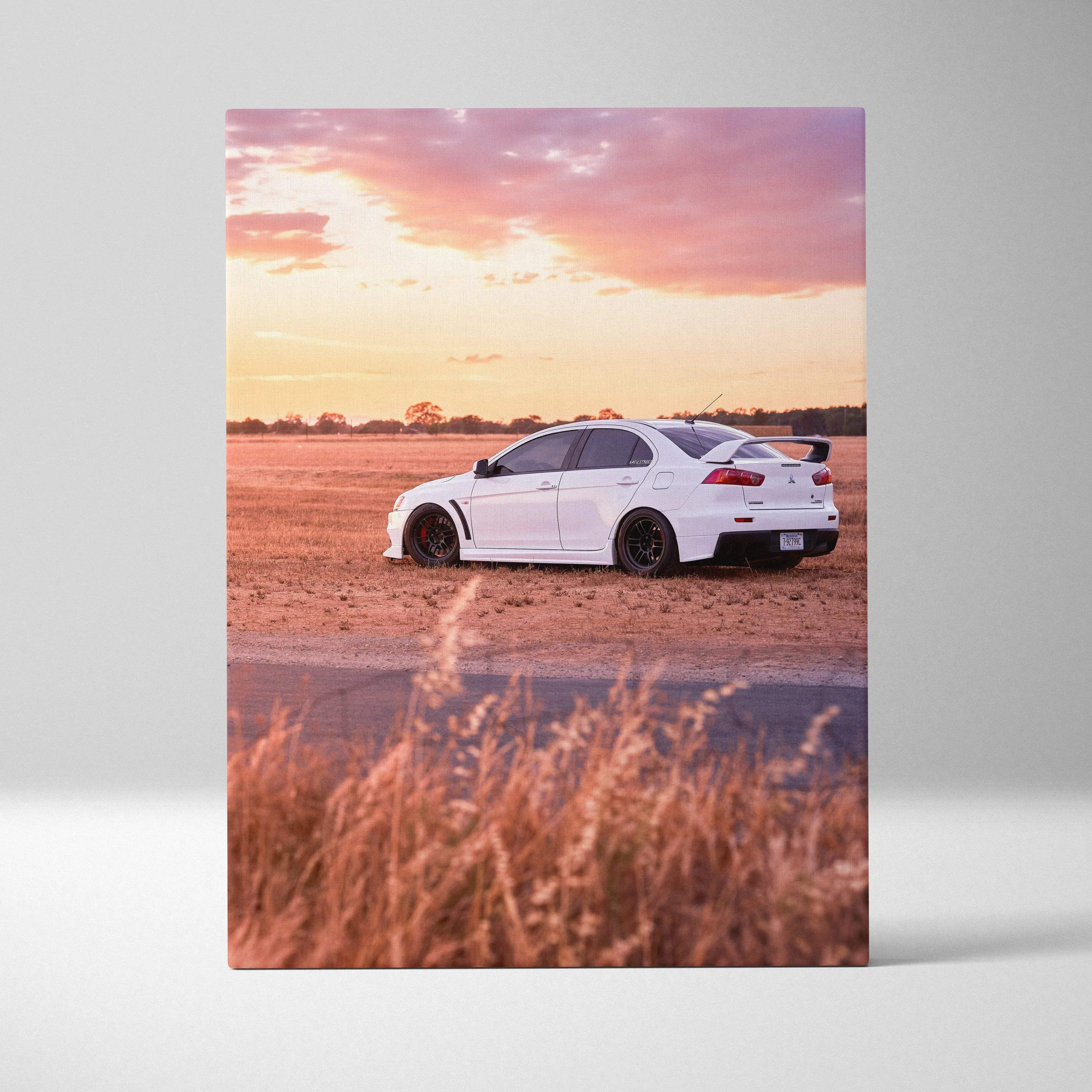 White Mitsubishi Evo 10 sports car on dirt road under pink sunset sky vertical canvas wall art.