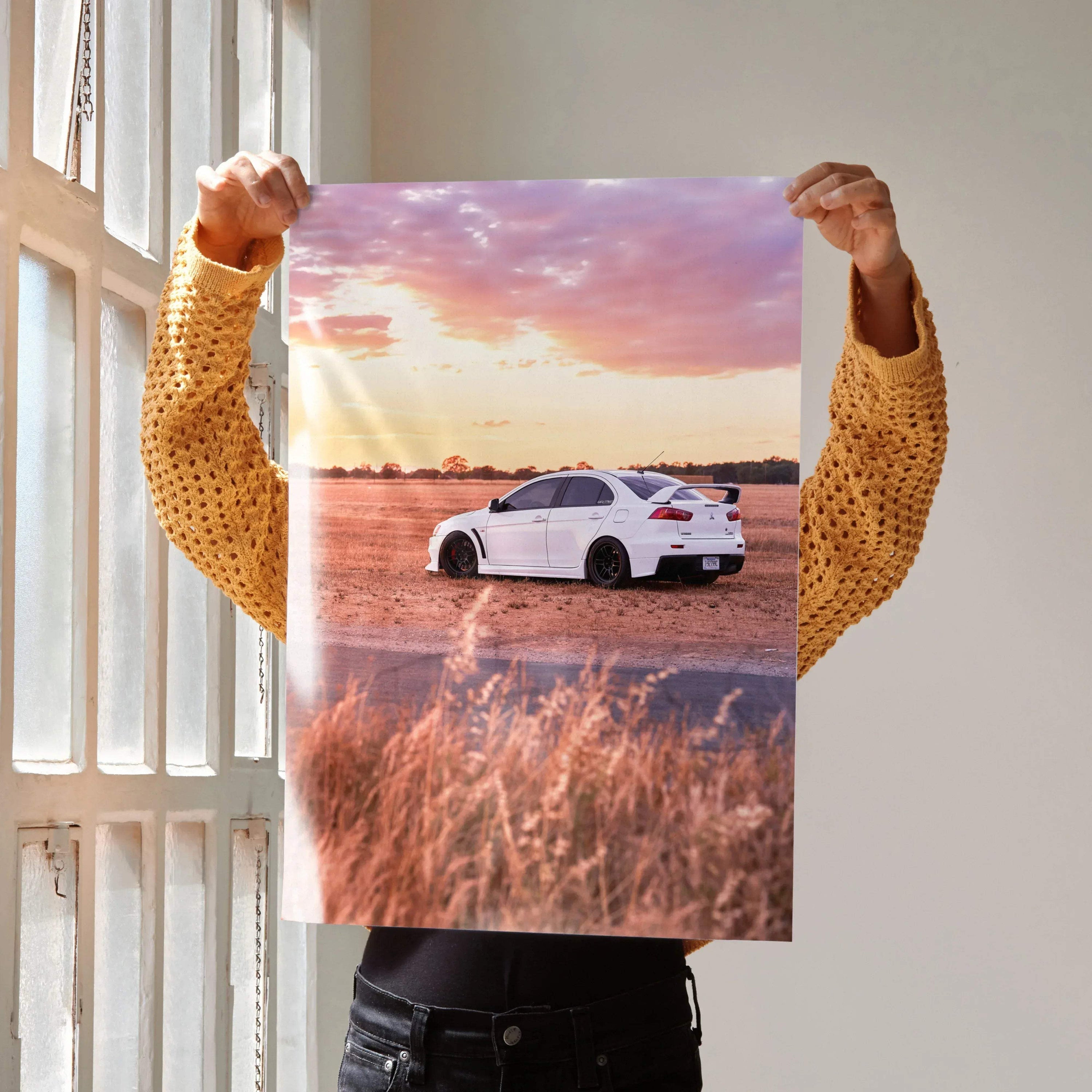 Mitsubishi Evo 10 white car driving at sunset poster wall art with vibrant sky and natural landscape.