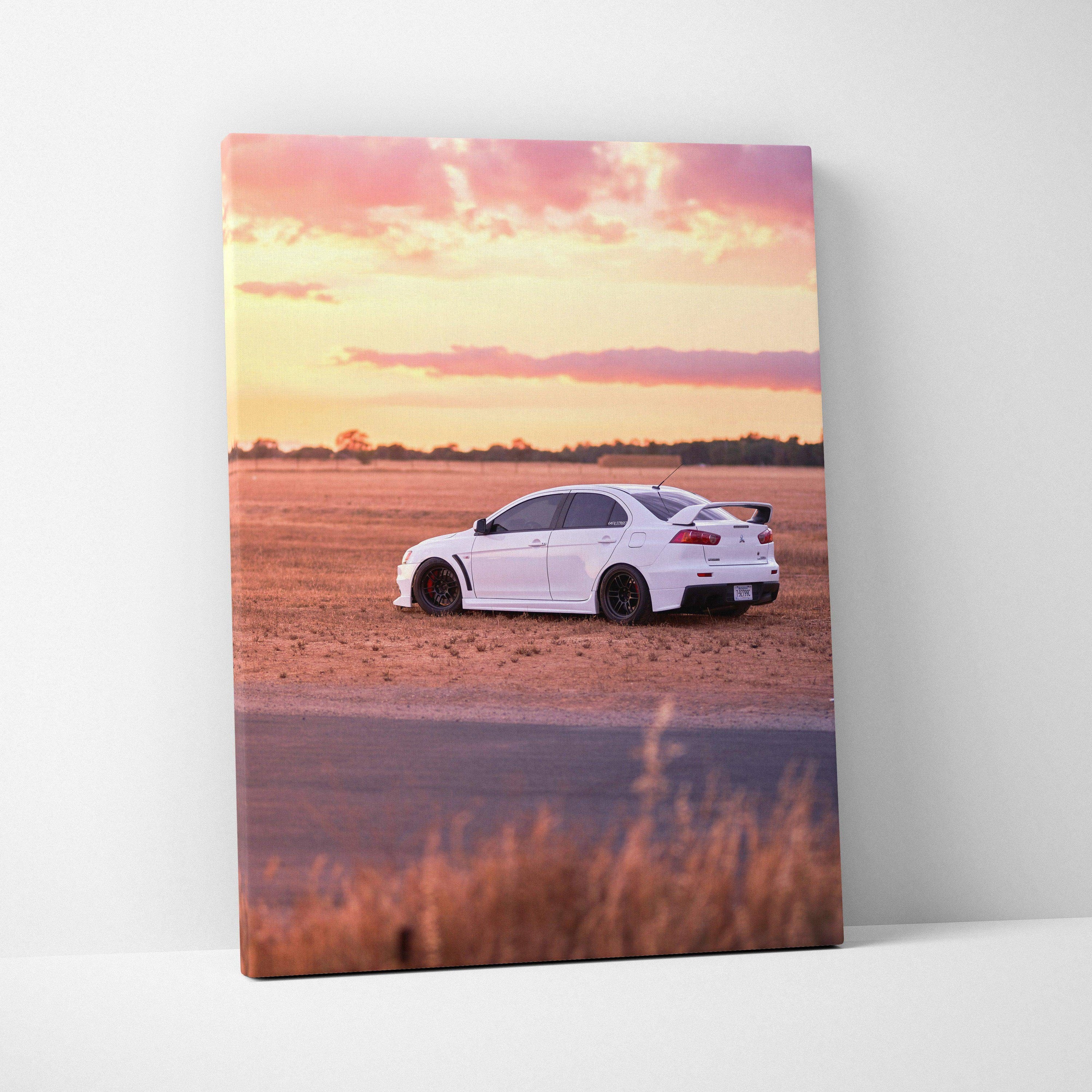 Vertical canvas art of a white Mitsubishi Evo 10 on a dirt field at sunset, warm tones wall art.