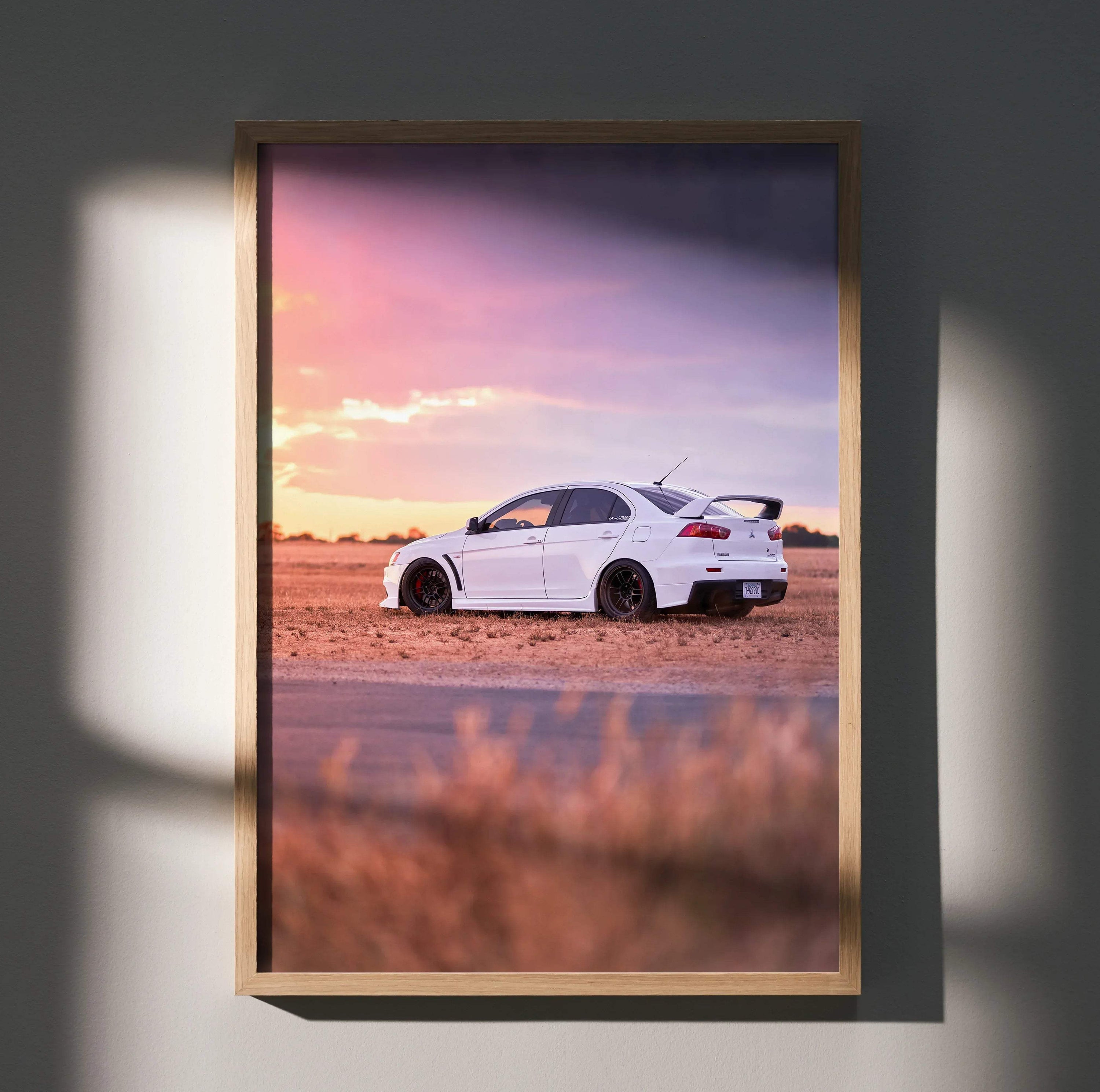 Mitsubishi Evo 10 poster featuring white car against vibrant sunset sky, wall art with warm tones.