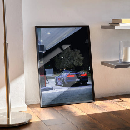Acura NSX poster wall art with nighttime urban car scene framed in black on hardwood floor.