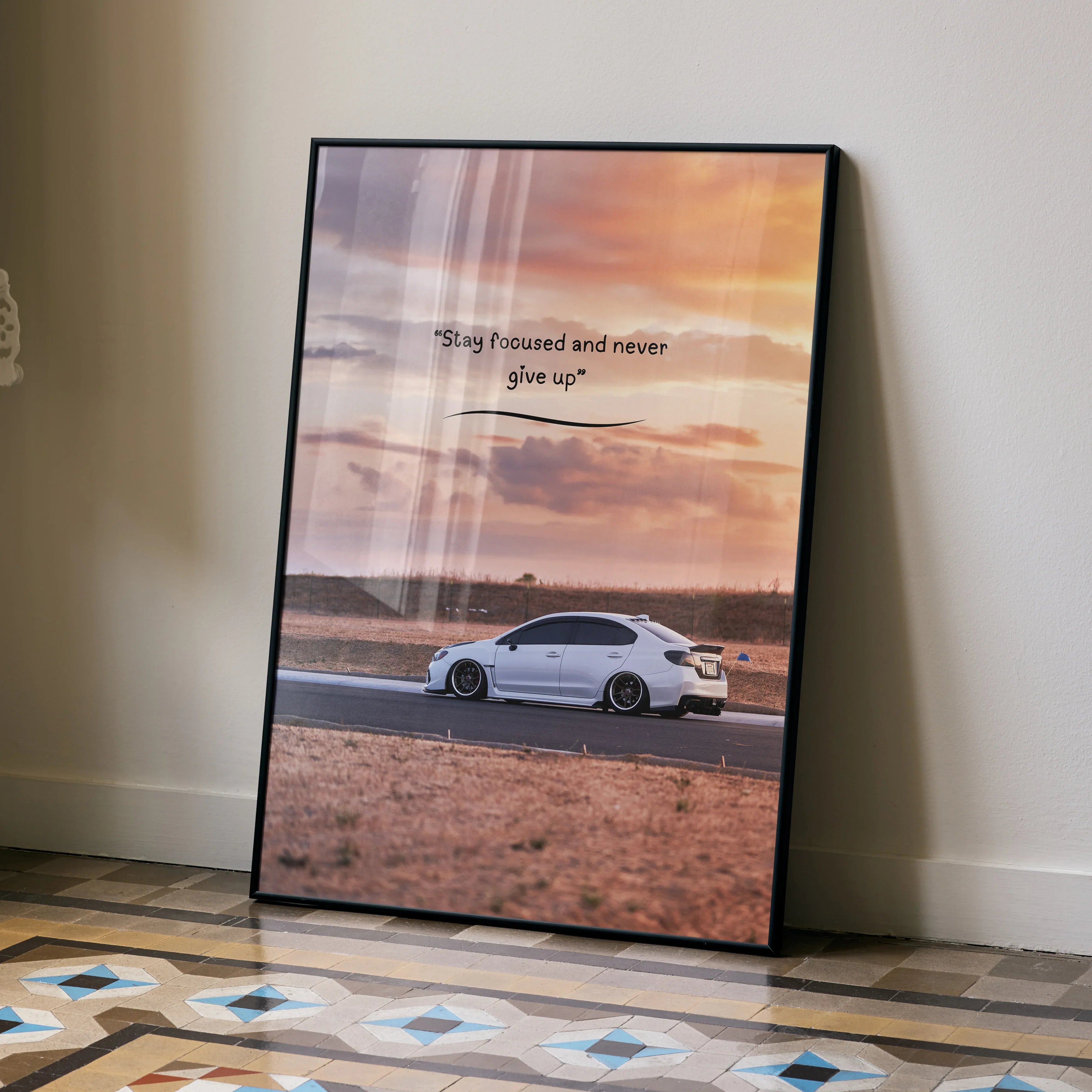 Motivational poster wall art featuring white Subaru WRX on desert road with sunset sky and inspiring text.