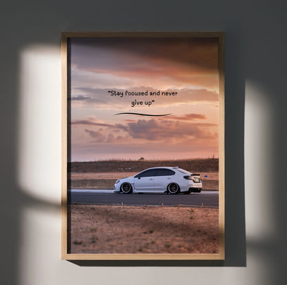Poster wall art featuring a white Subaru WRX on a desert road with motivating text "Stay focused and never give up" against.