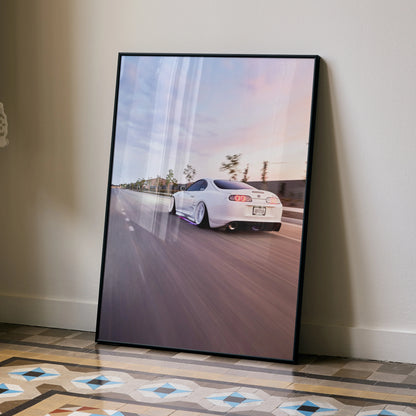 Supreme Toyota Supra MK4 speeding on road under sunset sky poster wall art in black frame.