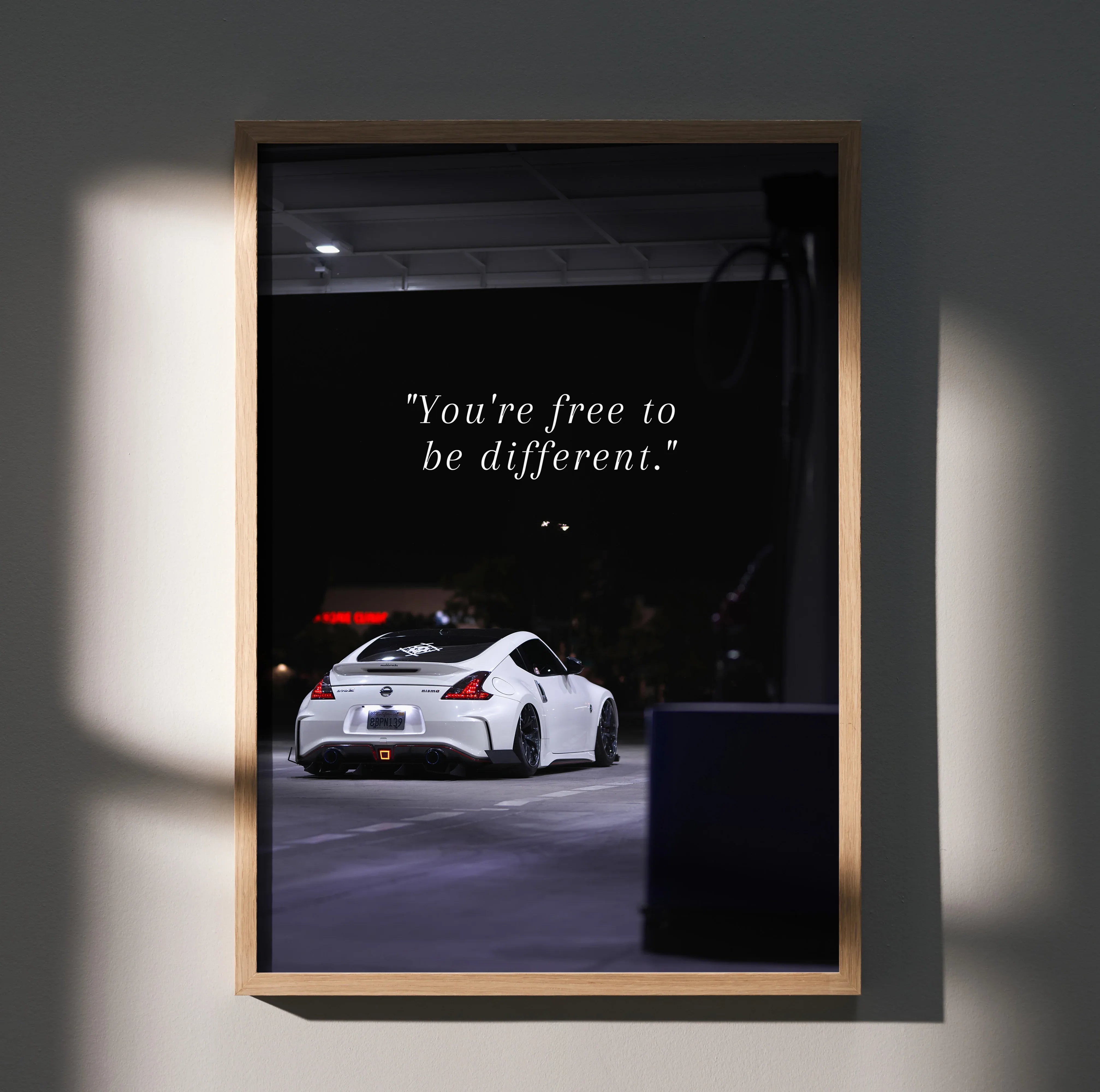 Motivational poster wall art featuring a white Nissan 370z with the text "You're free to be different" in a sleek black.