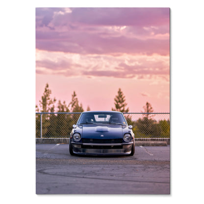 Nissan 240z poster with black car parked at sunset against pink and purple sky wall art.