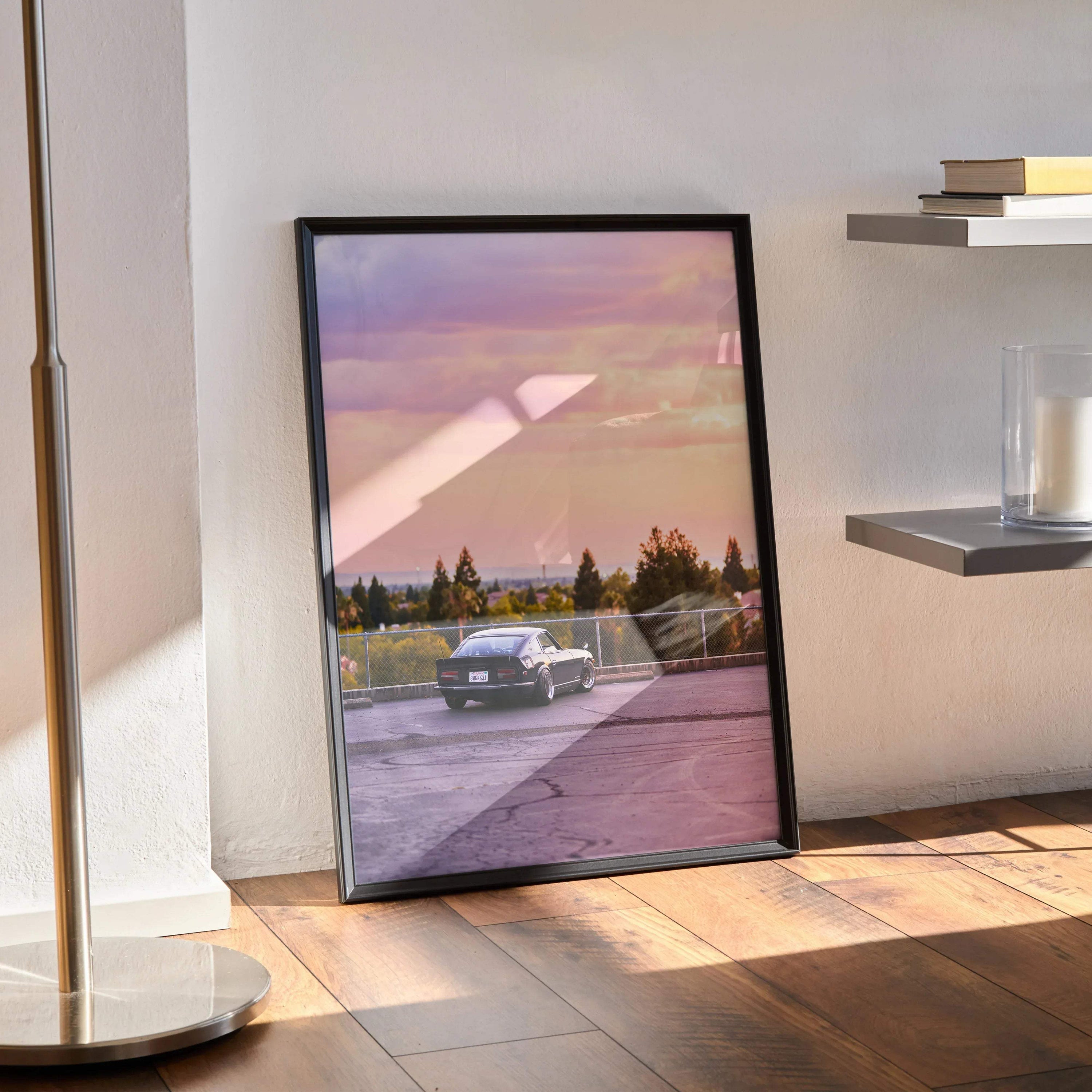 Nissan 240z poster wall art with scenic sunset and vintage car on road in black frame.