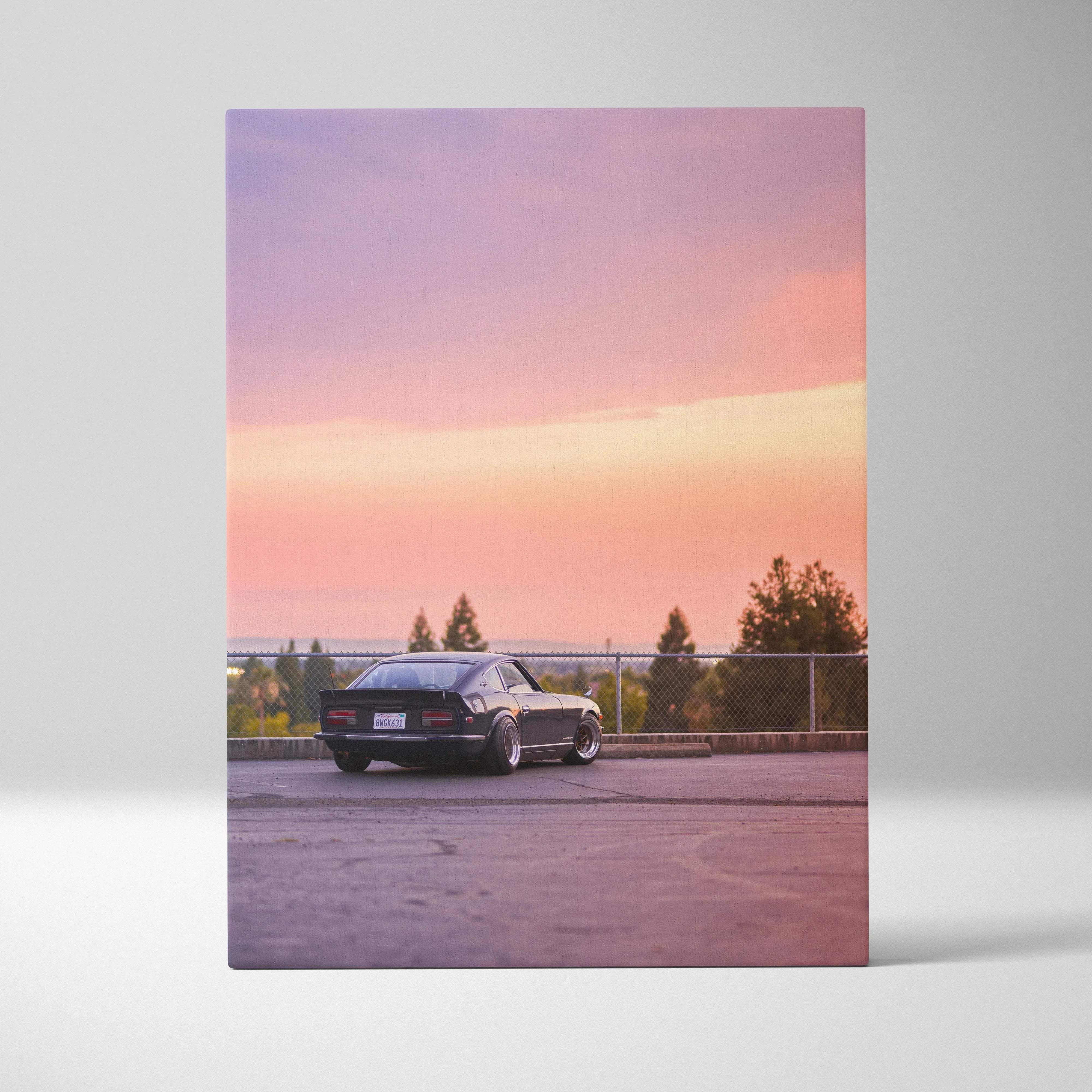 Black Nissan 240Z canvas wall art with sleek lines and lowered suspension against a pink and orange sunset sky