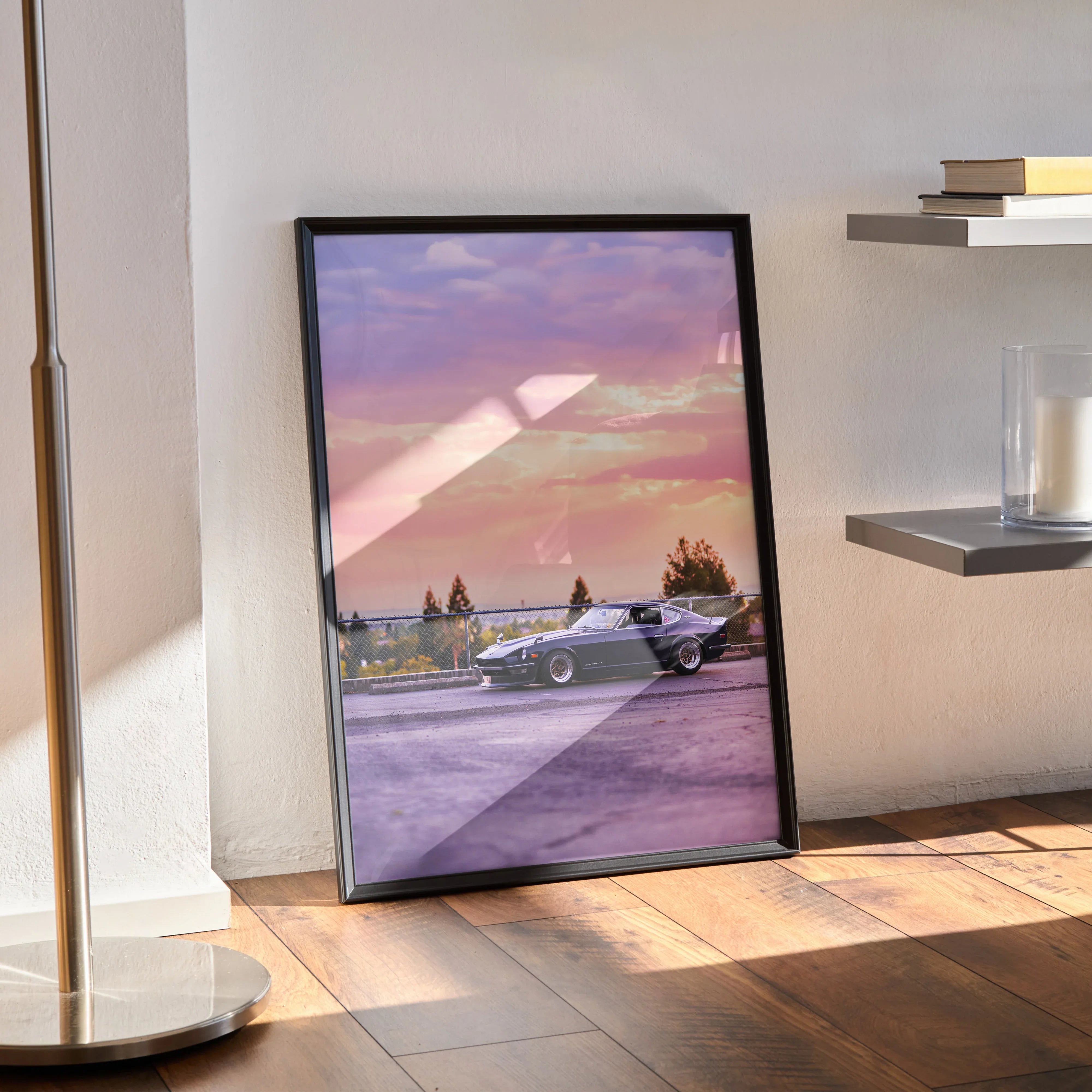 Nissan 240z car poster with purple sunset sky, framed wall art leaning against wall on wooden floor.