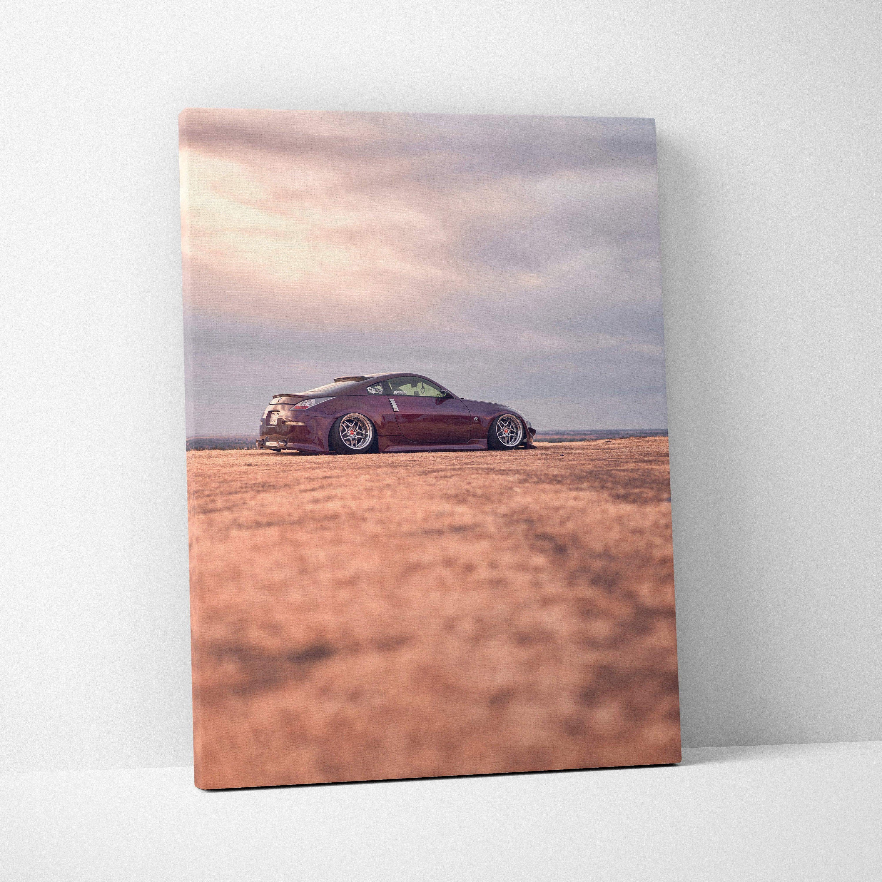 Vertical canvas art of a maroon Nissan 350z on a textured desert landscape under a cloudy sky, wall art print.
