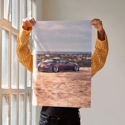 Nissan 350z poster featuring maroon sports car on sandy terrain under blue sky wall art.