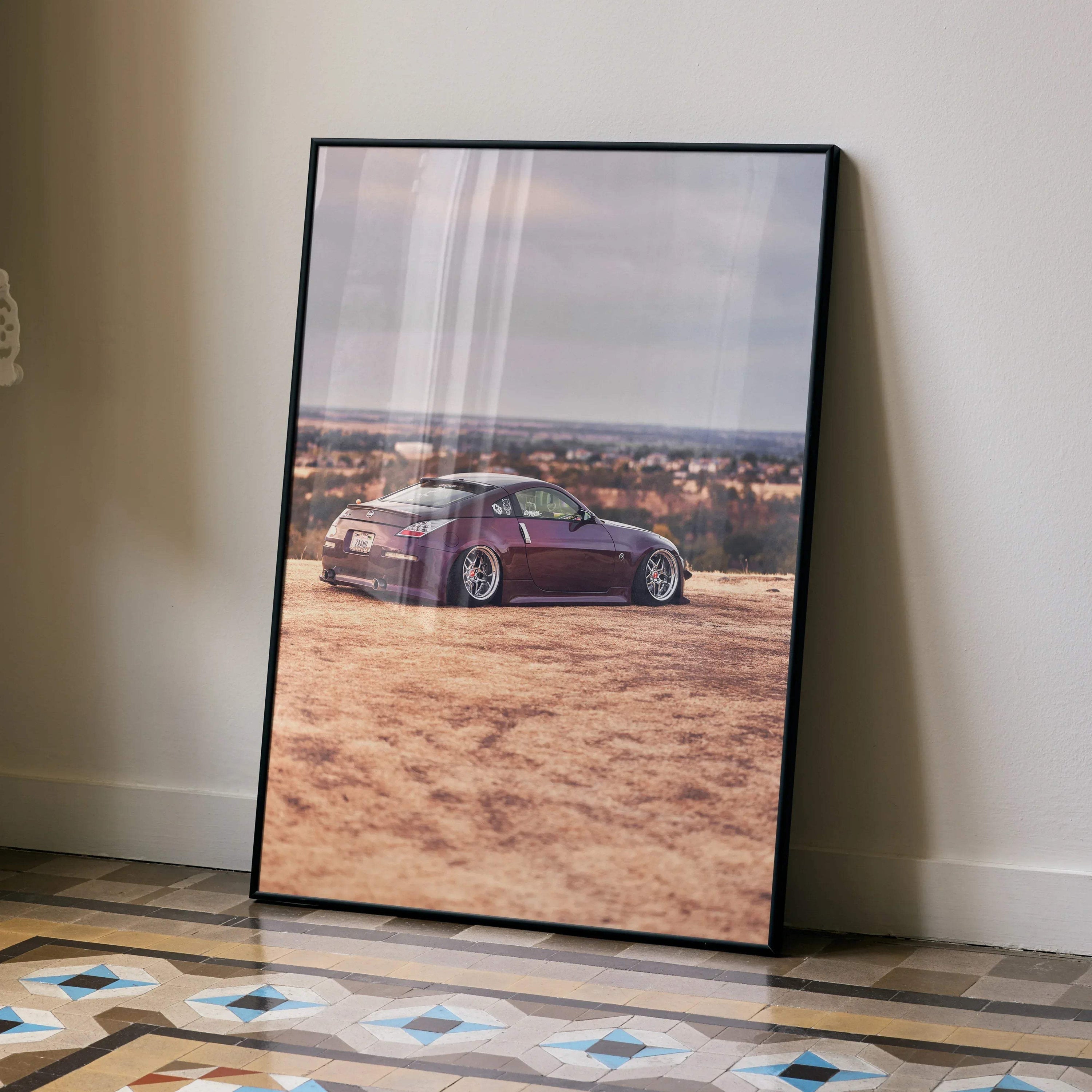 Nissan 350z poster wall art with maroon sports car on desert landscape in black frame.