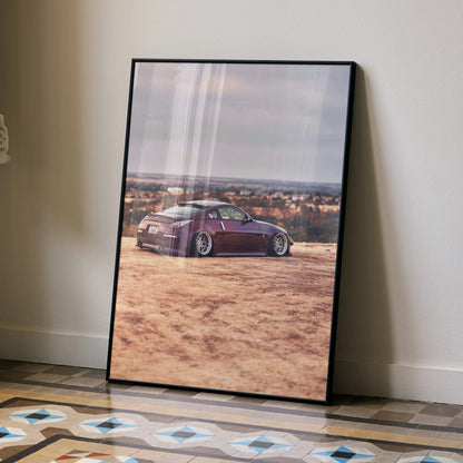 Nissan 350z poster wall art with maroon sports car on desert landscape in black frame.