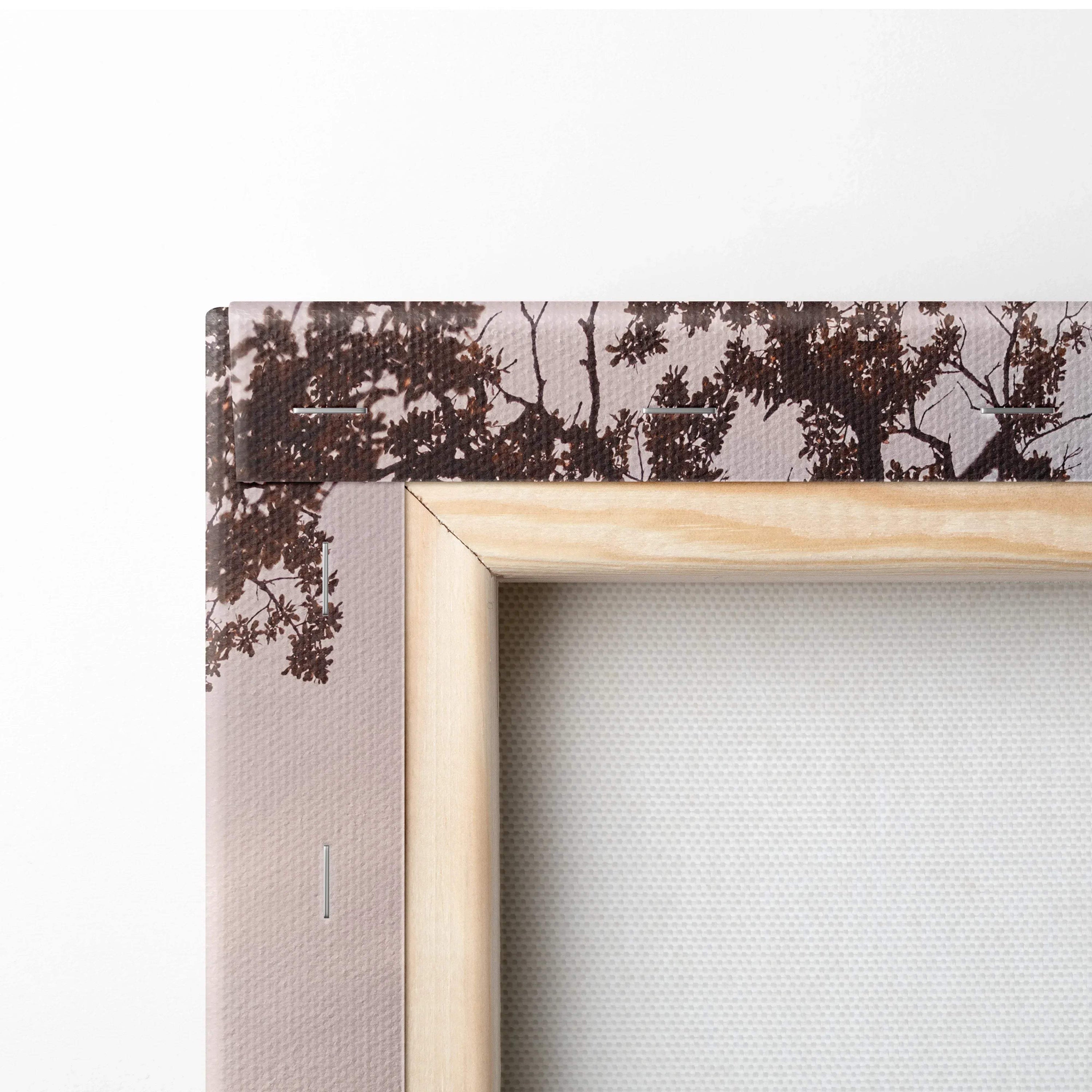 Close-up of wooden frame and textured canvas edge with dark tree silhouette, vertical wall art detail.