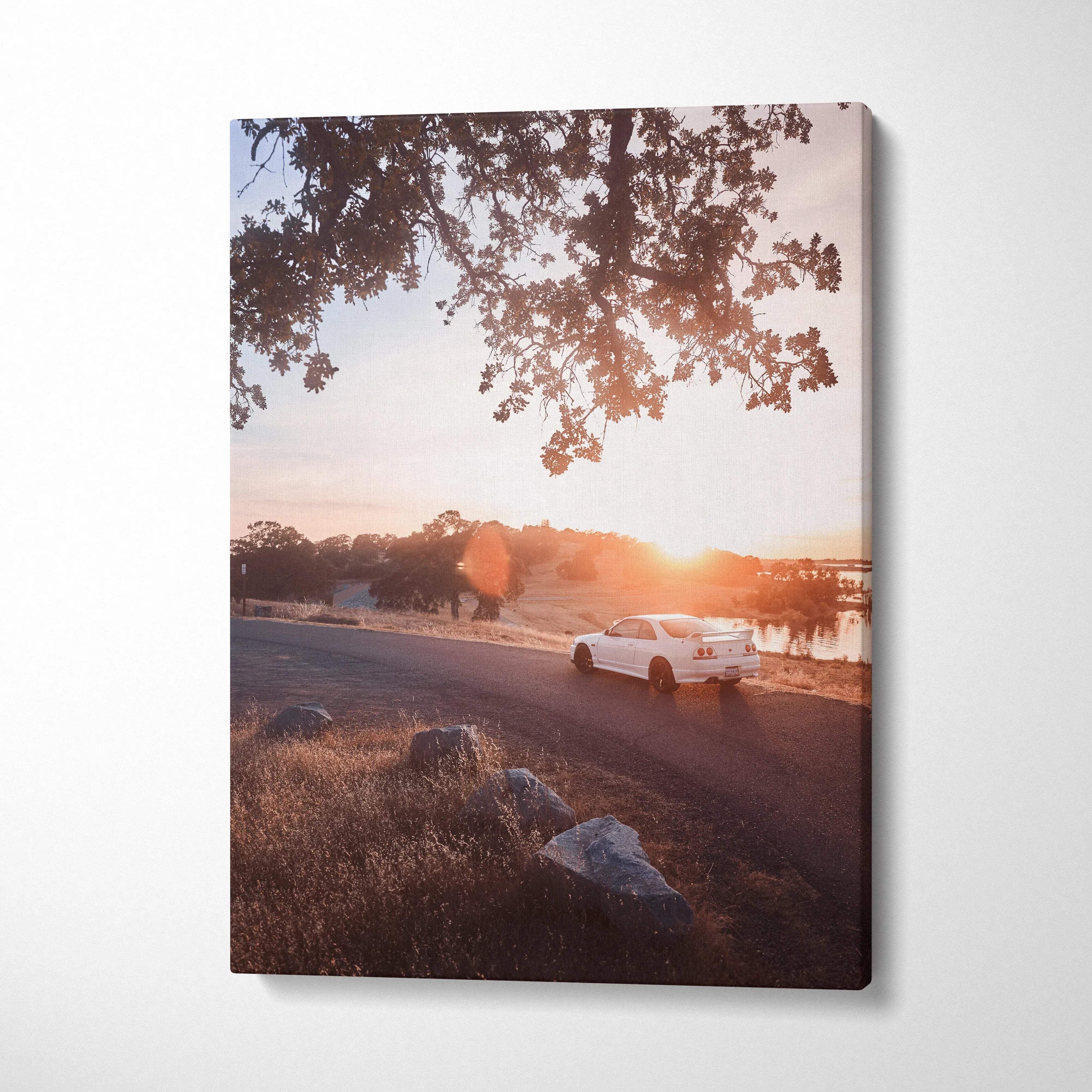 Vertical canvas wall art of a white Nissan R33 GTS-T driving at sunset with tree branches overhead.