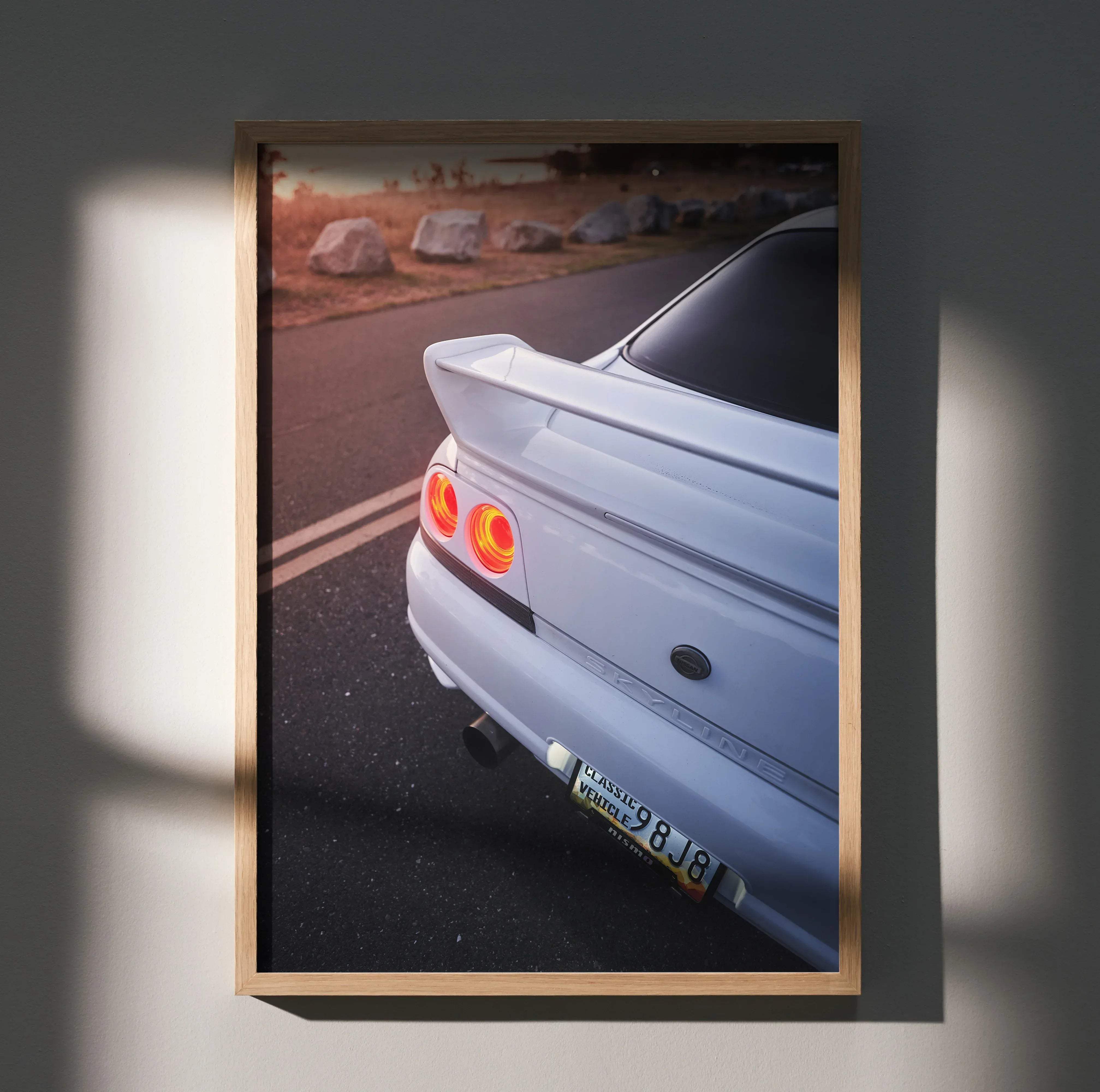Framed photograph of a white Nissan Skyline R34 with glowing red taillights and rear spoiler for car enthusiast decor