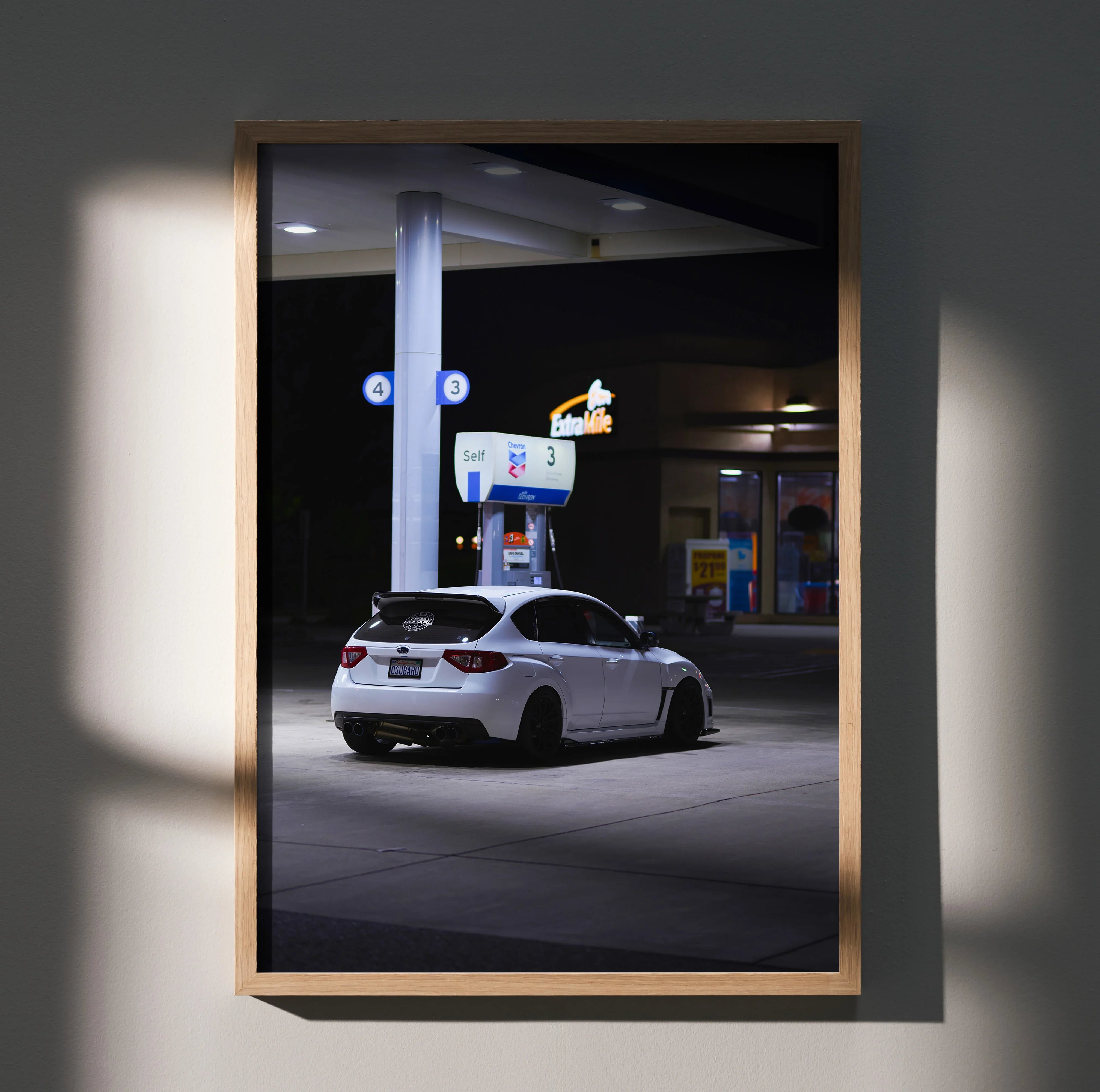 Subaru WRX STI parked at gas station at night poster wall art in wooden frame.